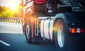 Red Semi Truck Speeding on a Highway. Tractor Closeup. Transportation and Logistics Theme.